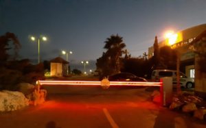 מחסום זרוע מואר באור אדום בלילה, מוצב בכניסה למתחם.