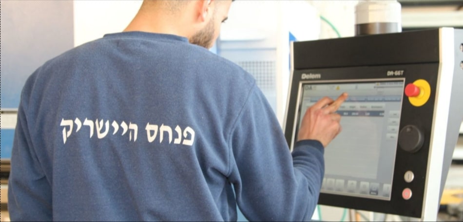 עובד מתעסק בלוח מחשב שכנראה מחובר למכונה תעשייתית ניתן לראות כפתורים בצדו של המחשב בצבע אדום צהוב שחור כסוף וורוד