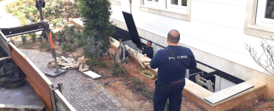 התקנה של סבכה בצבע שחור המיועדת לחצר אנגלית בבית פרט ,ניתן לראות שתי עובדים אשר אחד מכוון את ההנפה שלה והשני מקבל אותה לתוך המסגרת עצמה